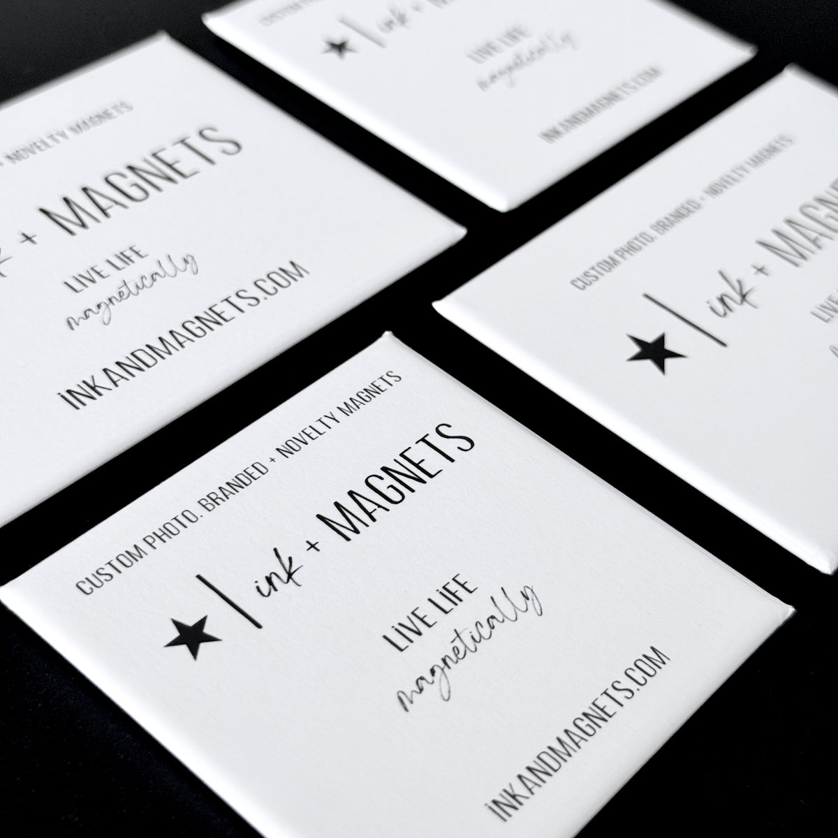 Ink and Magnets branded business card magnets on a black background.