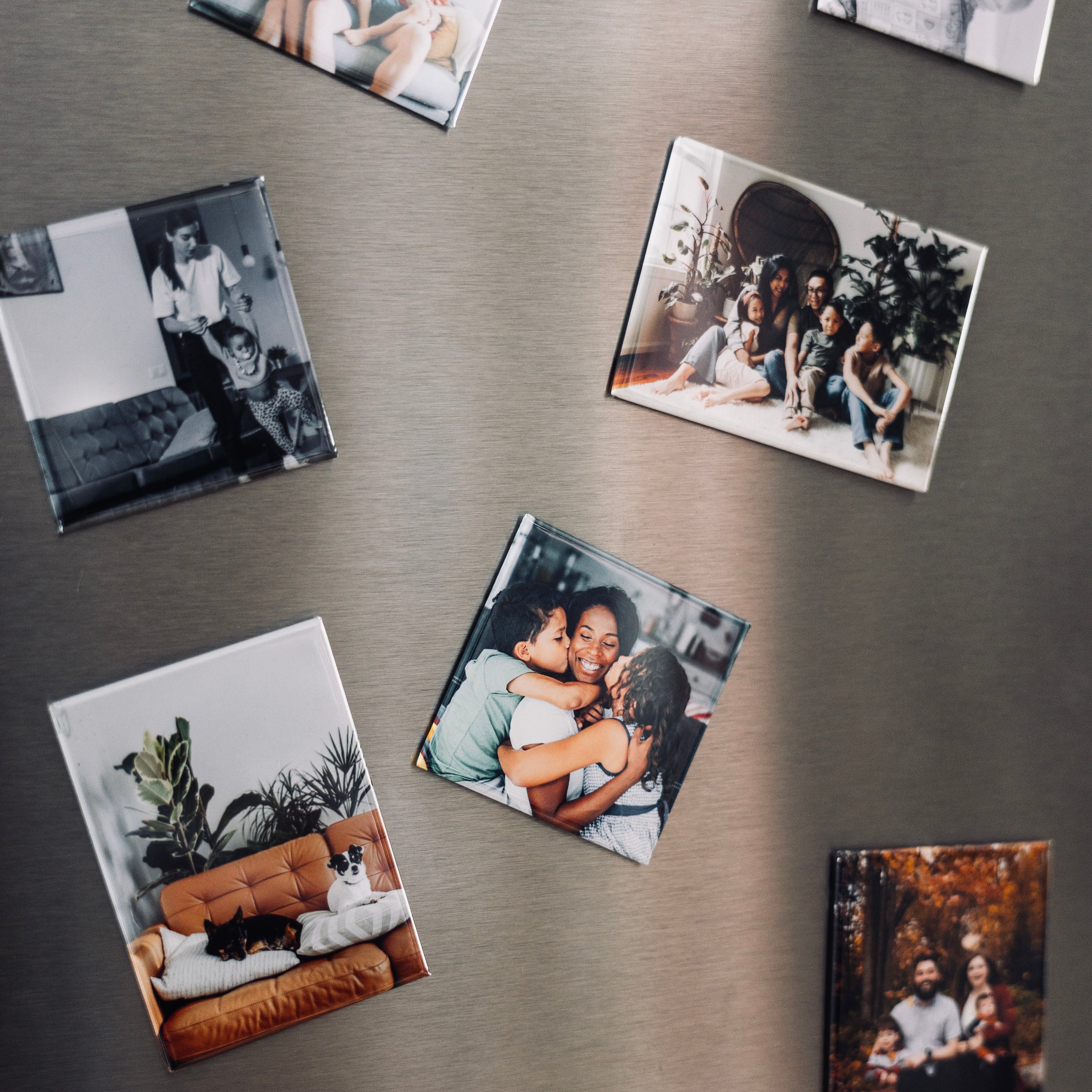 Collection of magnetic photo prints on a stainless steel fridge. 