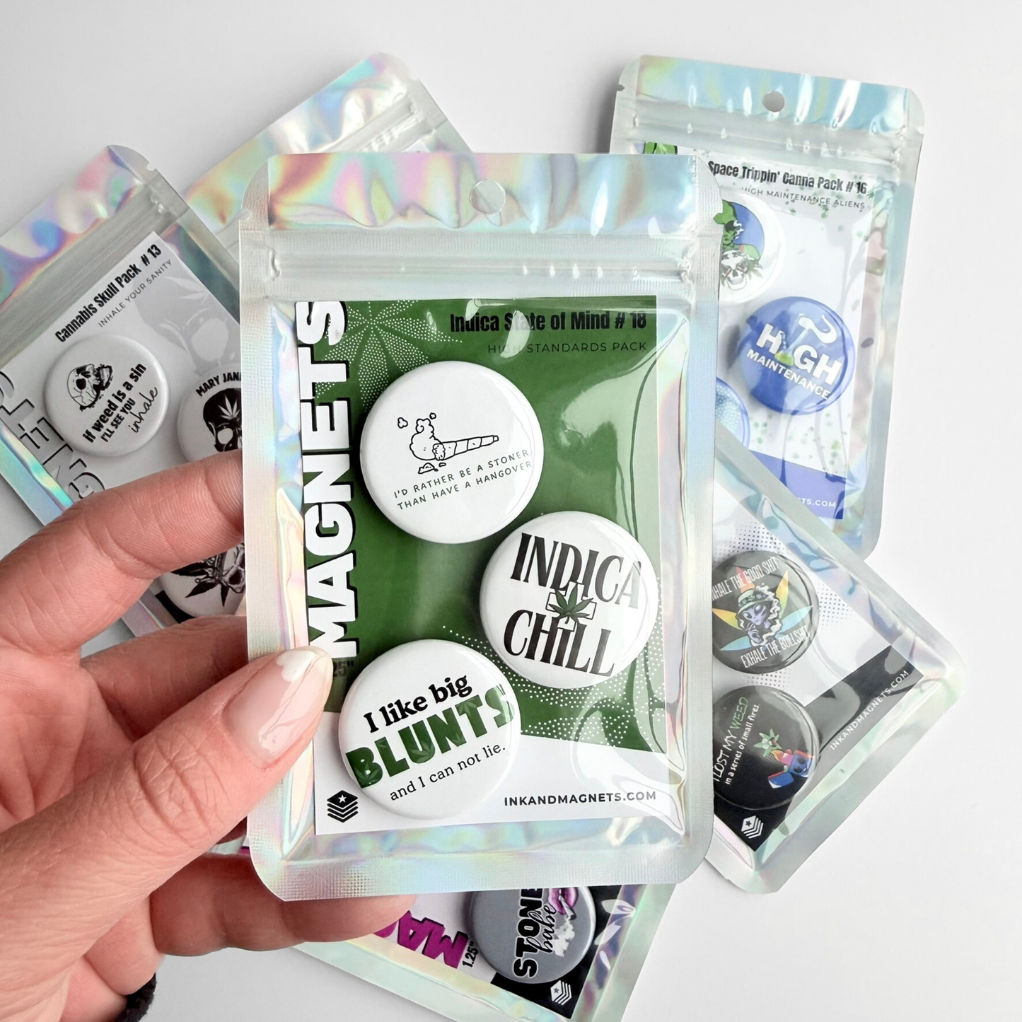 Cannabis culture novelty magnet pack held in hand, featuring humorous weed-themed fridge magnets in collectible magnet sets also available as a pin pack.