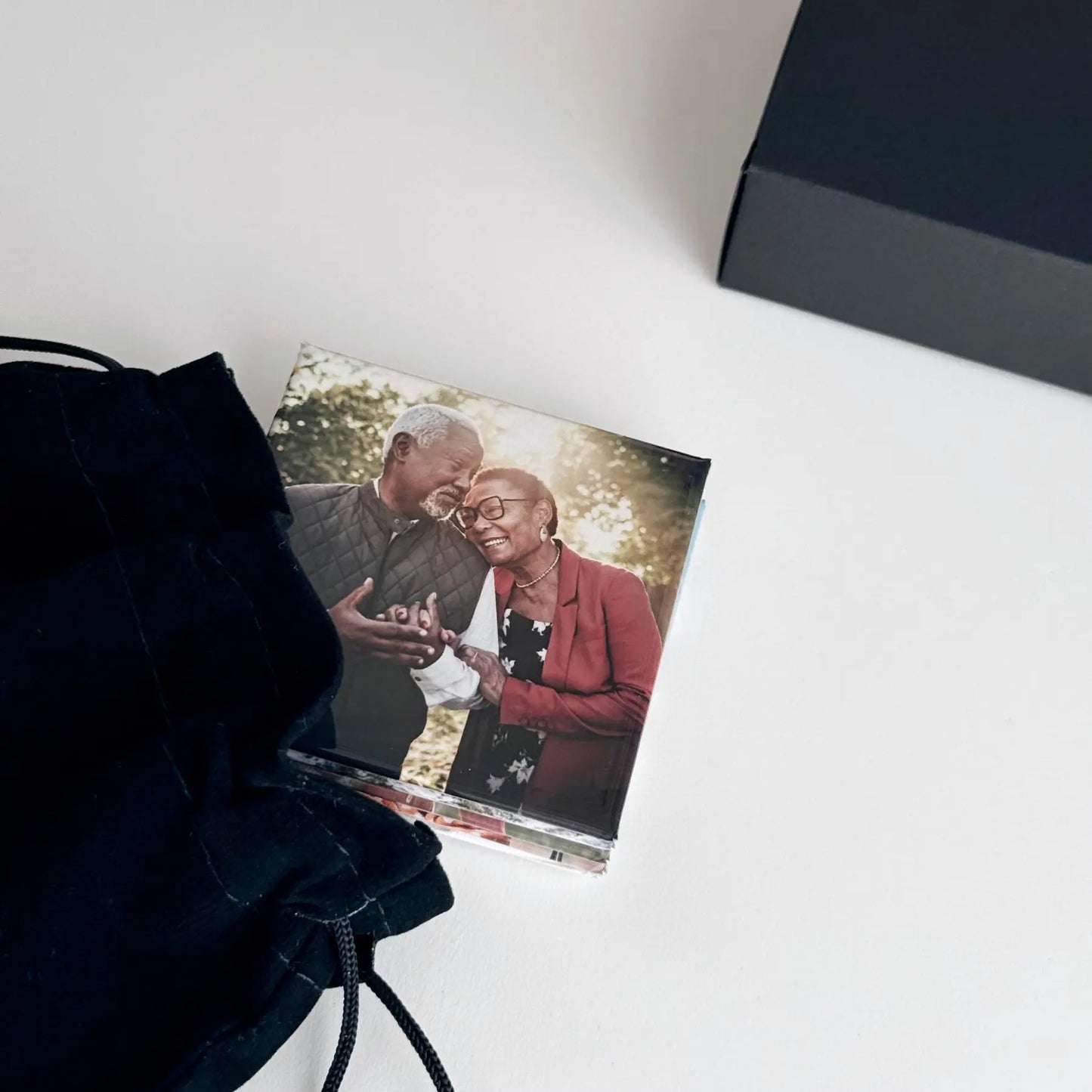 Small order of square custom printed photo magnets featuring a happy older couple celebrating a milestone. Magnets are featured next to elegant gift ready packaging.