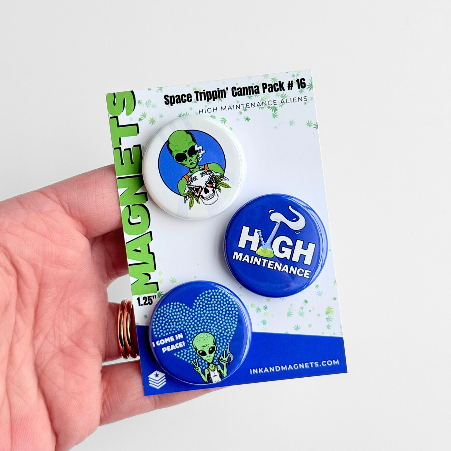 420 themed button magnet pack with alien graphics and high maintenance humor, displayed in hand as a novelty fridge magnet set