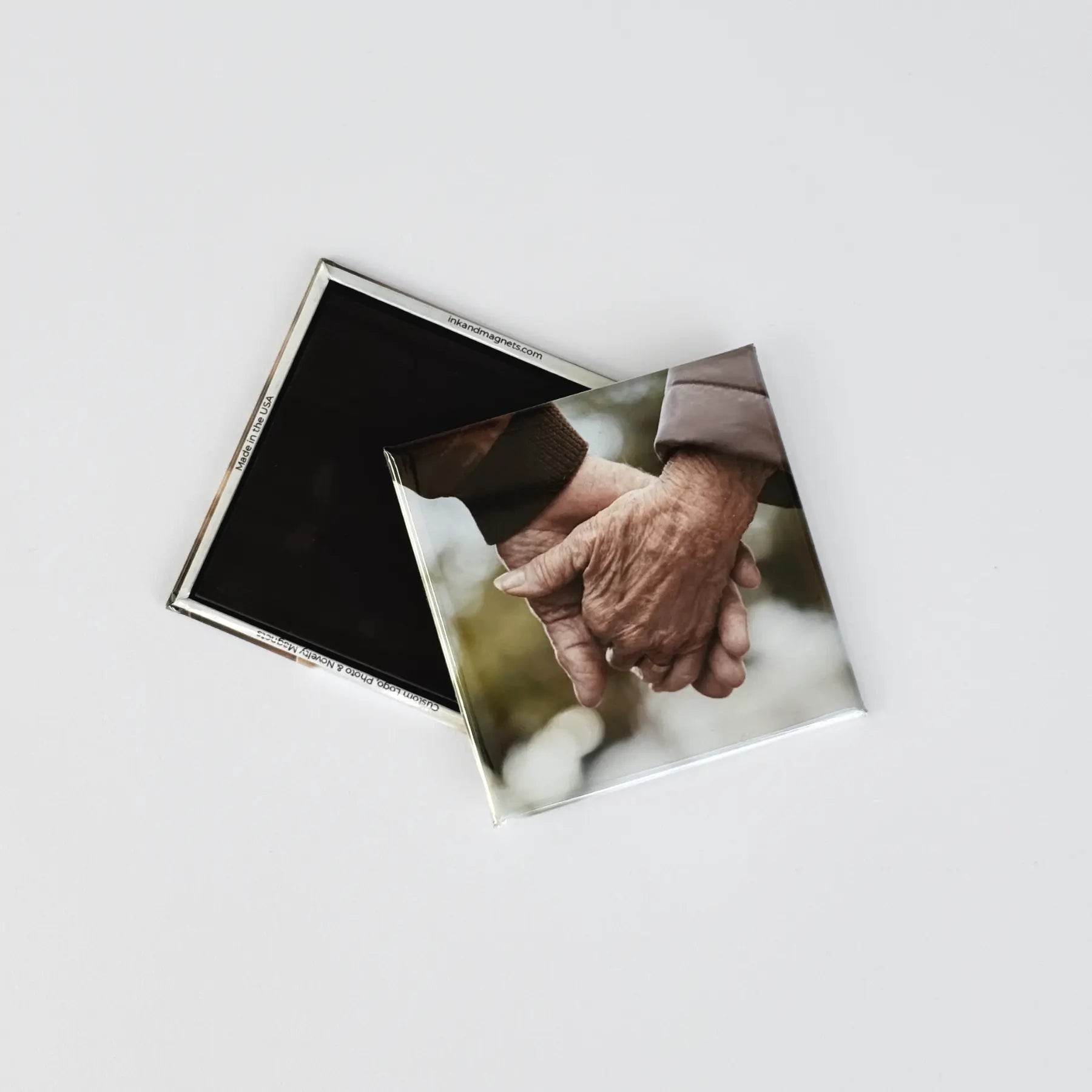 Closed corner square button magnets displaying the front and back of custom photo magnets. Front features a sentimental personalized image of a couple holding hands.
