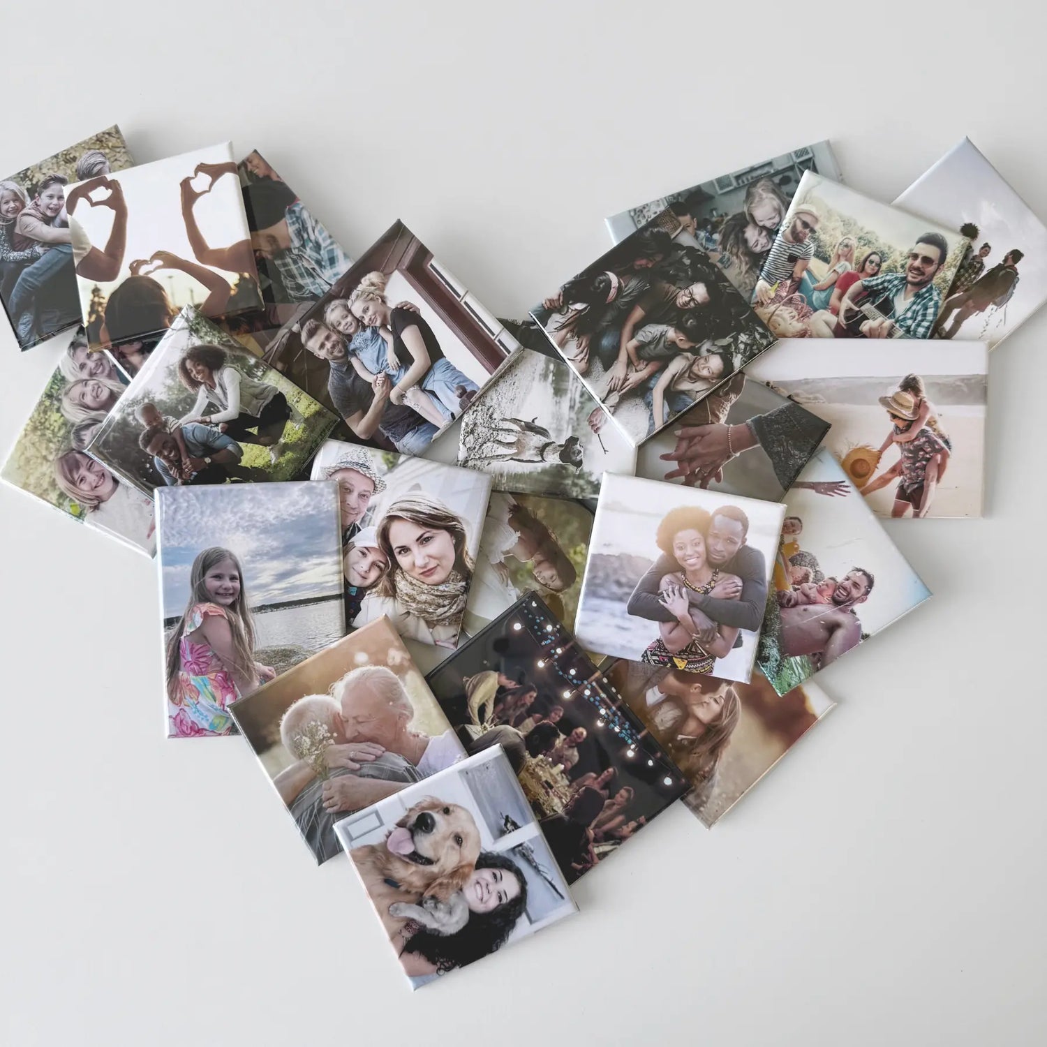 Custom photo magnets arranged in a heart shape on a white surface, showcasing diverse family memories, with partners, kids, and pets. Share them as a small emotional support gift to remind someone of what they mean to you.