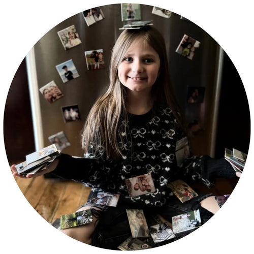 Young girl proudly holding and displaying all her family memory fridge magnets.