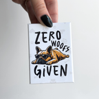 Funny novelty button magnet with a dog illustration and text 'Zero Woofs Given' held by a hand.