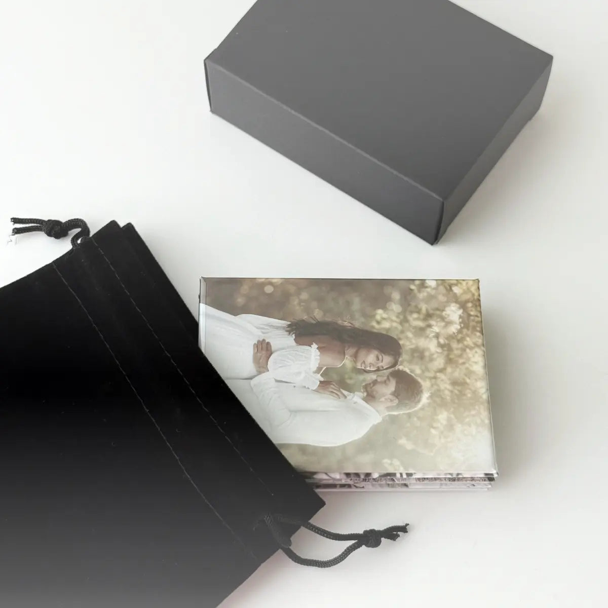 Custom photo magnets being shown with sleek black gift bag and box. Product and gift packaging for personalized fridge photo gifts.